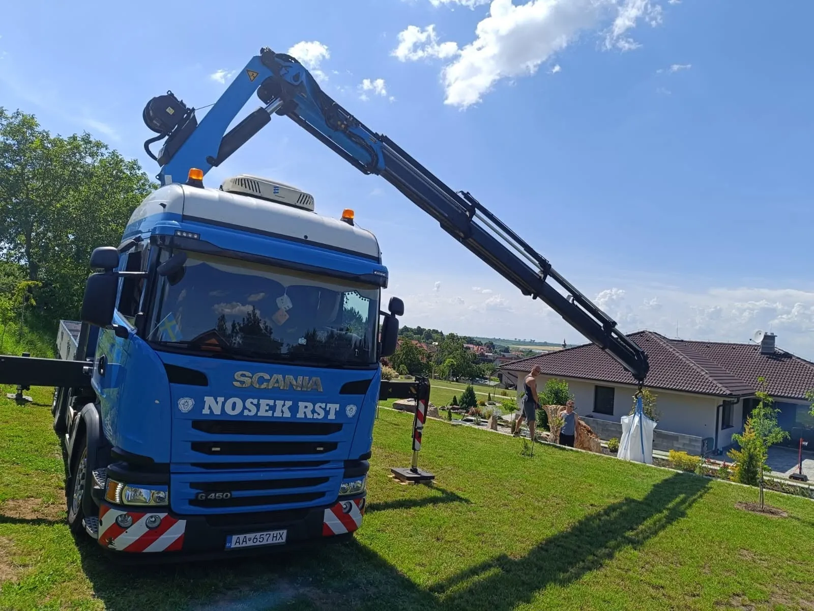 Nákladné vozidlo Scania s hydraulickou rukou pri práci v záhrade